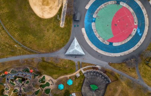 An aerial top view over an empty park with different ball courts for sports and playground areas